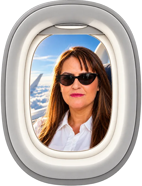 Ana Carla Moura sorrindo de óculos escuros, vista pela janela de um avião